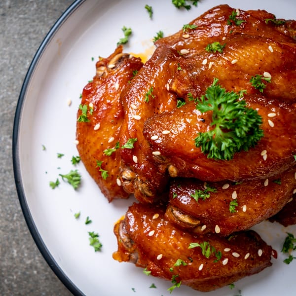 Close-up of Magic Wings & Things' glazed chicken wings, garnished with sesame seeds and parsley.