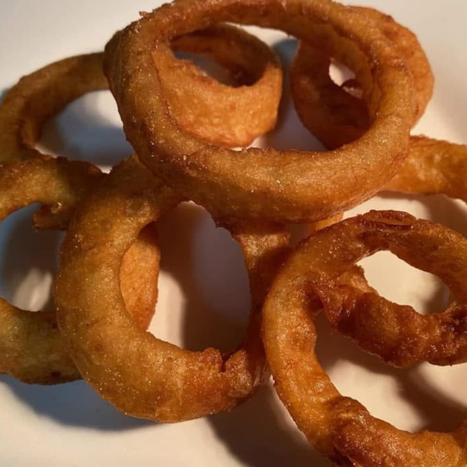 Close-up of golden-brown, crispy curly fries on a white surface.